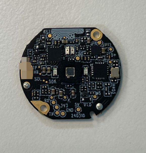 Close view of a round populated circuit board with components and gold-colored mounting holes.